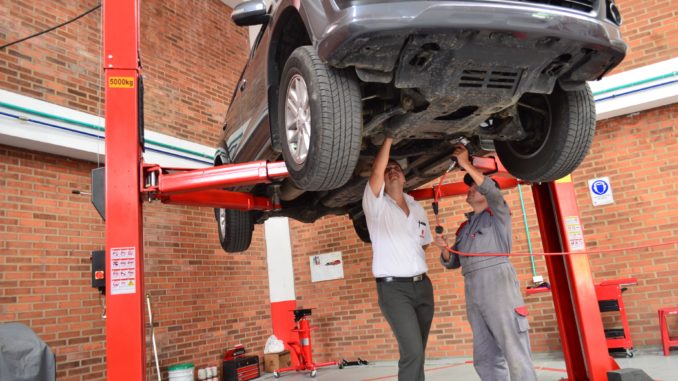 Kfz-Werkstatt: zwei Personen unter einem Auto auf einer Hebebühne